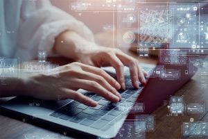 Hands typing on a laptop. Various charts, graphs and data visualizations are overlayed on the photo.